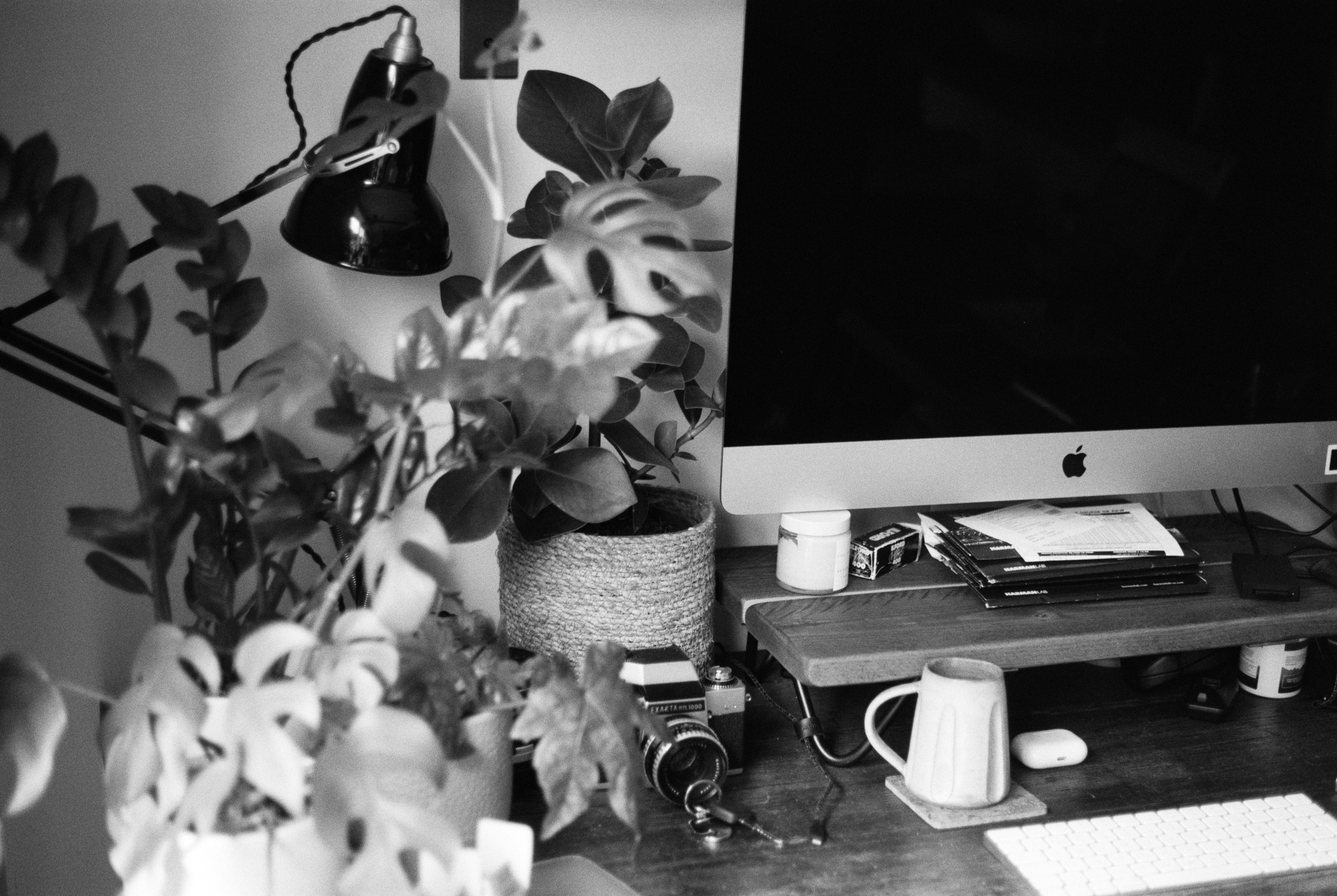 grayscale photo of black desk lamp on table